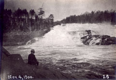 Un visiteur assis sur un rocher observe les es chutes de Shawinigan.