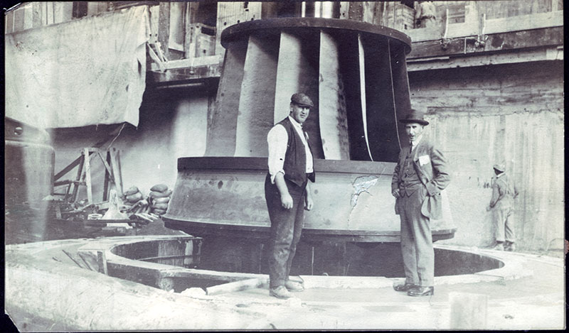 A worker installs a Francis turbine under the watchful eye of his foreman.
